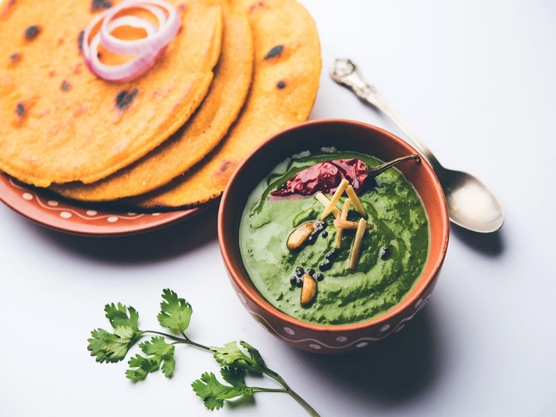 Makki di roti with sarson ka saag, popular punjabi main course recipe in winters made using corn breads mustard leaves curry. served over moody background. selective focus